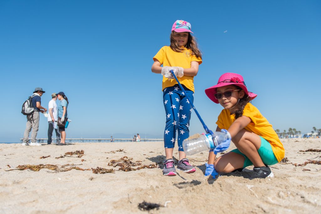 photo of a woman and a child picking up trash at a beach